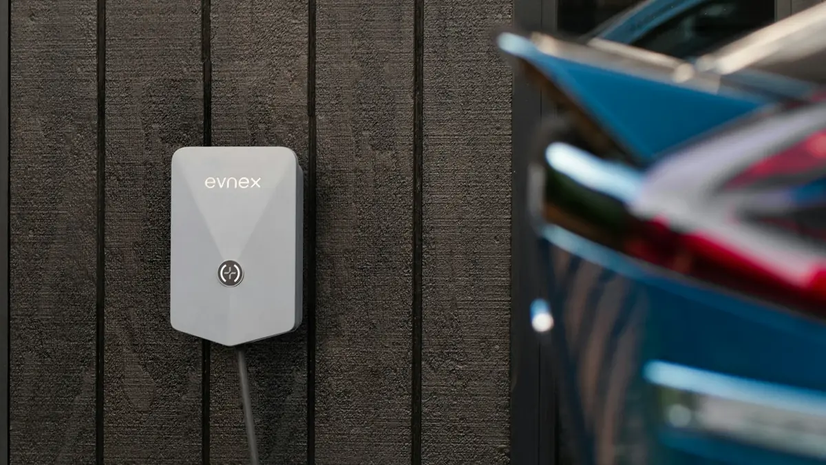Laadpaal voor de elektrische auto aan een houten schutting